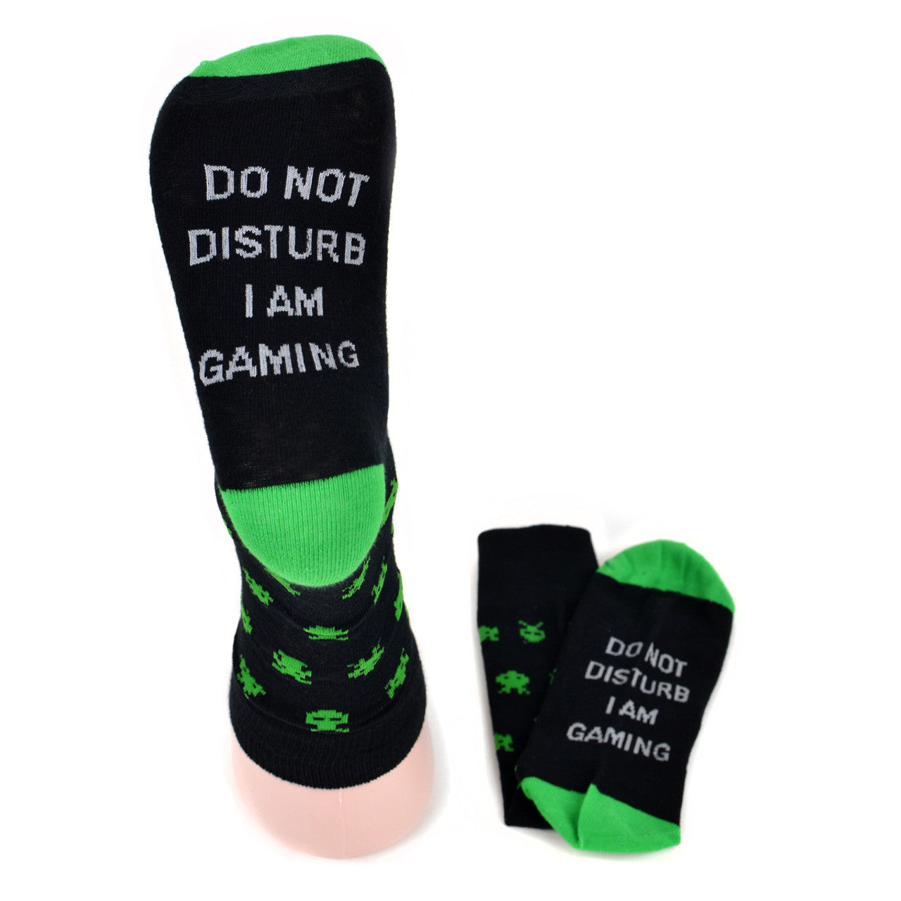 A pair of black crew-length socks with a vibrant green toe, heel, and top trim, featuring an all-over pattern of green pixelated space invaders. The soles of the socks display the phrase "DO NOT DISTURB I AM GAMING" in bold, white capital letters, and the top of the foot showcases a detailed grey gaming controller with colorful buttons. These are signature gaming socks, perfect for the avid gamer. LifeisSocks.com