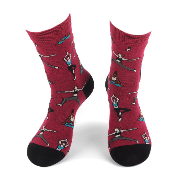 A pair of red socks featuring illustrations of people in various yoga poses. The socks have black toes and heels and showcase characters practicing yoga in diverse positions such as tree pose, warrior pose, and seated meditation.