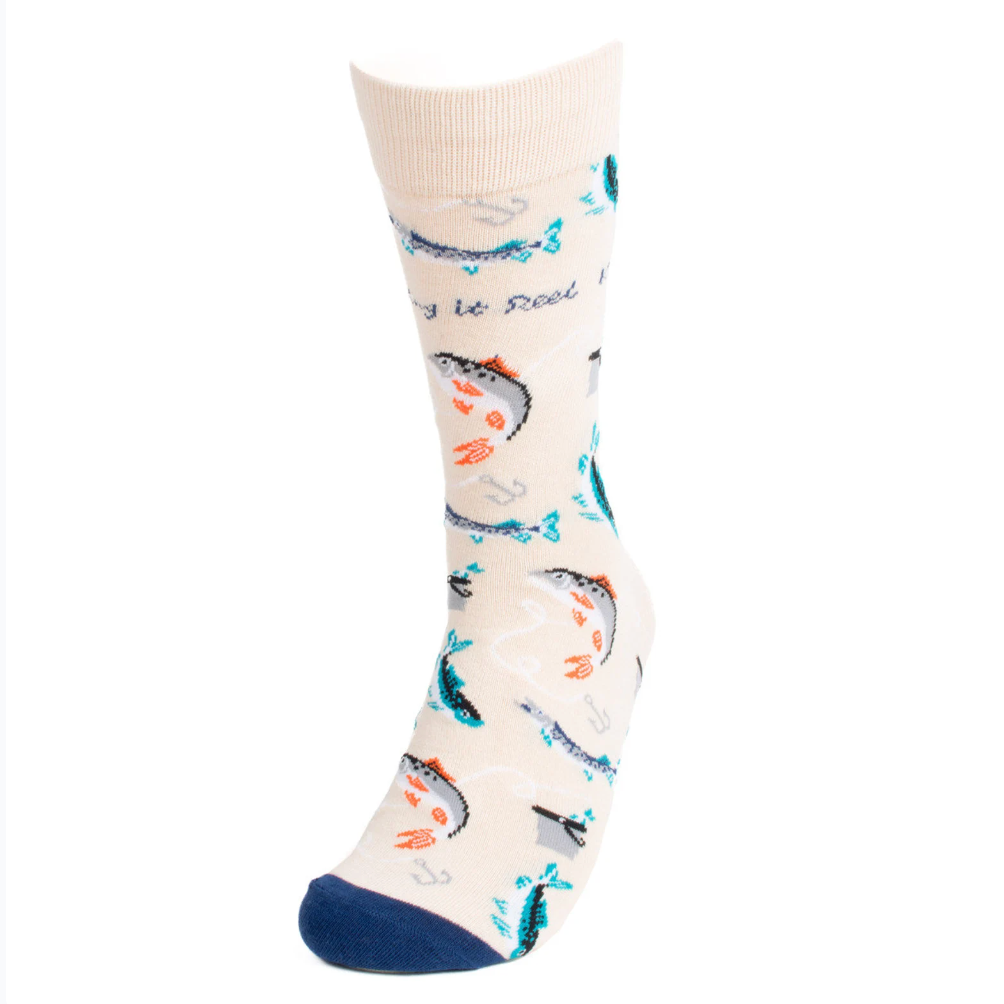 A pair of cream-colored men's socks featuring a playful fishing theme. The socks are decorated with various fish, fishing hooks, and anchors in shades of blue, teal, and orange. The phrase "Keeping it Reel" is scattered throughout the design. The toes are accented with a navy blue color.