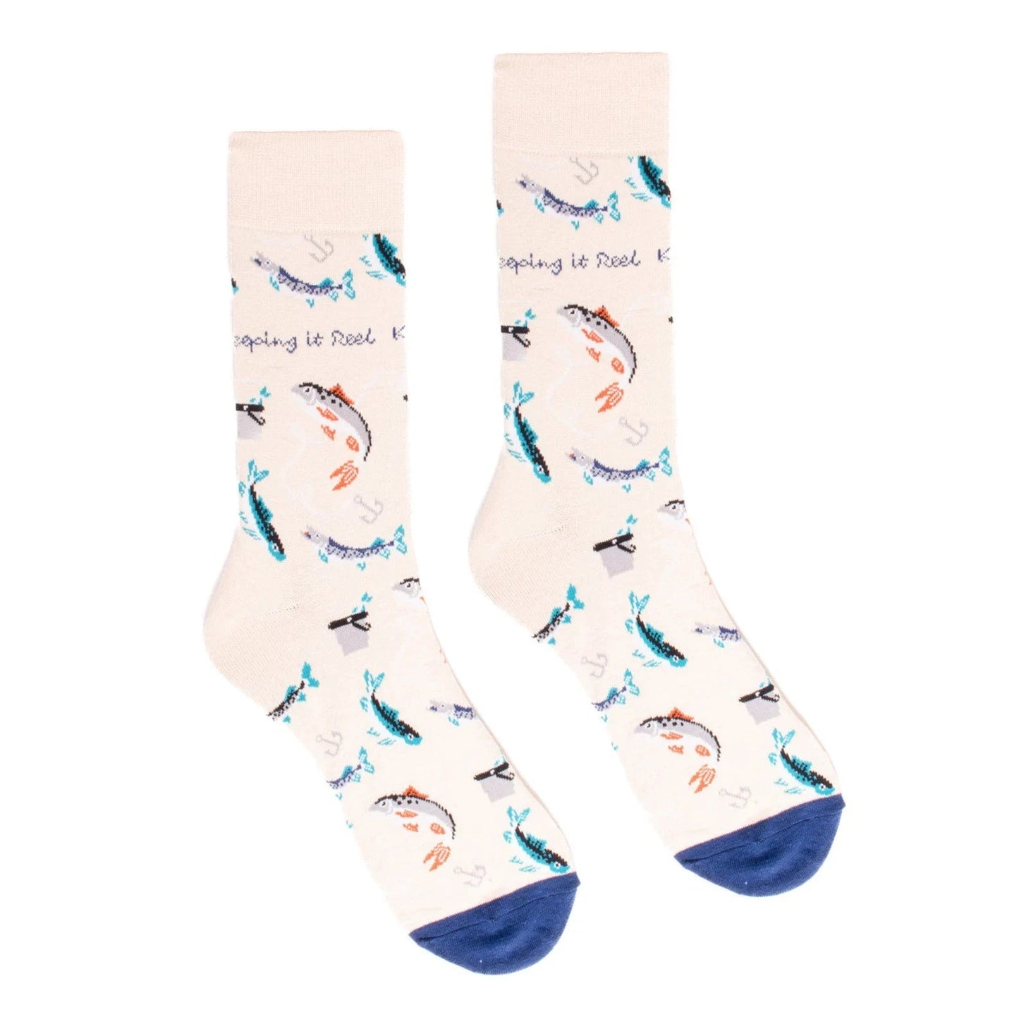 A pair of cream-colored men's socks featuring a playful fishing theme. The socks are decorated with various fish, fishing hooks, and anchors in shades of blue, teal, and orange. The phrase "Keeping it Reel" is scattered throughout the design. The toes are accented with a navy blue color.