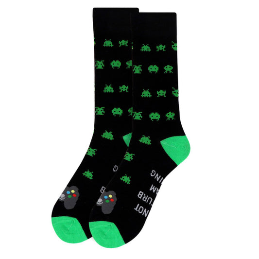 A pair of black crew-length socks with a vibrant green toe, heel, and top trim, featuring an all-over pattern of green pixelated space invaders. The soles of the socks display the phrase "DO NOT DISTURB I AM GAMING" in bold, white capital letters, and the top of the foot showcases a detailed grey gaming controller with colorful buttons. These are signature gaming socks, perfect for the avid gamer. LifeisSocks.com