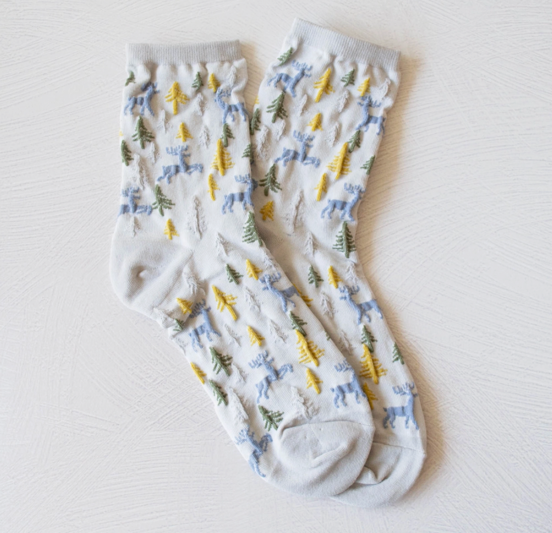 Light gray cozy winter cabin socks featuring woodland deer reindeer and trees.