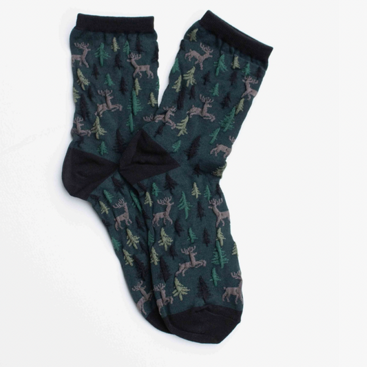 Dark green and black cozy winter cabin socks featuring woodland creatures and trees. Brown deer.