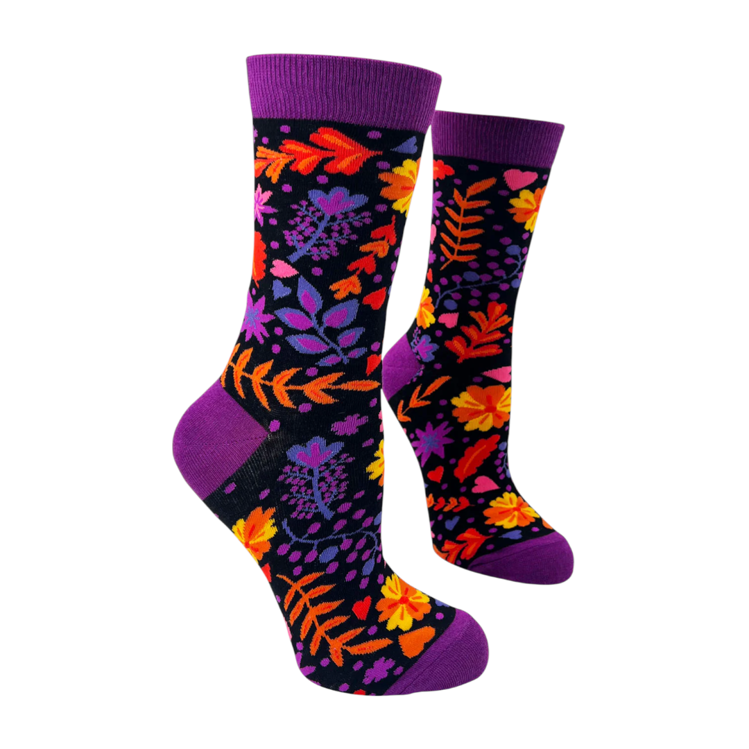 Women’s floral print crew sock with purple cuff on black background featuring bright flowers, leaves, and small heart accents