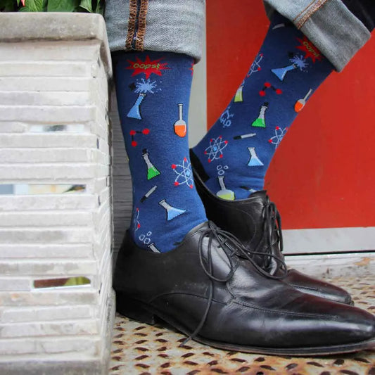 Man wearing blue socks with science and chemistry designs and black shoes.