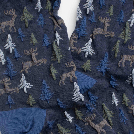 Women's holiday forest socks with deer and pine tree pattern. Blue socks with brown, blue and olive textured design.