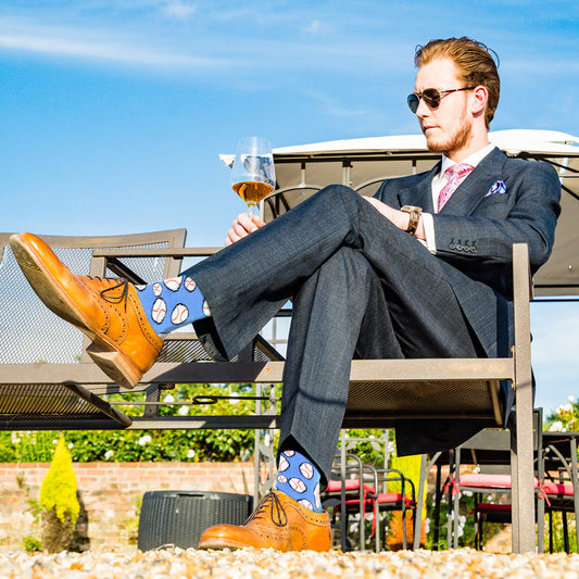 Men's Baseball Crew Socks - Blue with baseball pattern. Black toe and heel. Modeled by a man in a suit.