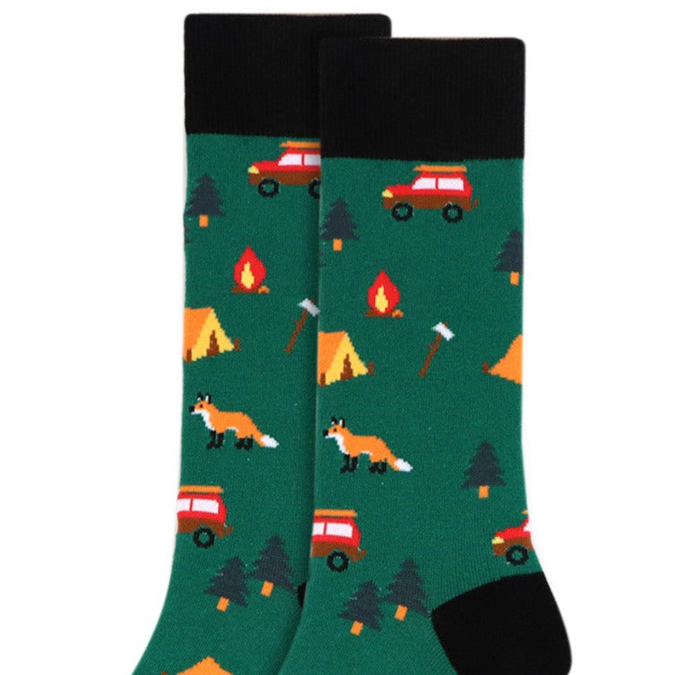 A pair of green camping crew socks with a pattern that includes tents, a fox, and a campfire.