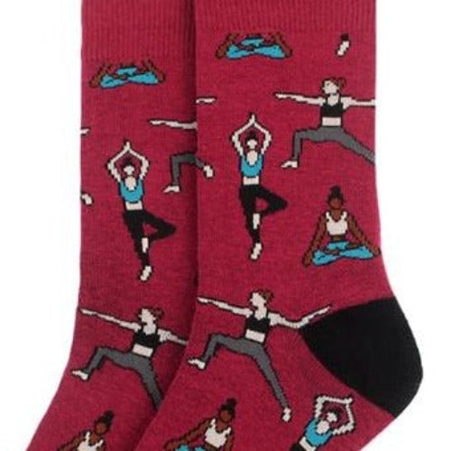 A pair of red socks featuring illustrations of people in various yoga poses. The socks have black toes and heels and showcase characters practicing yoga in diverse positions such as tree pose, warrior pose, and seated meditation.